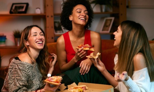 three girls eating pizza indoors