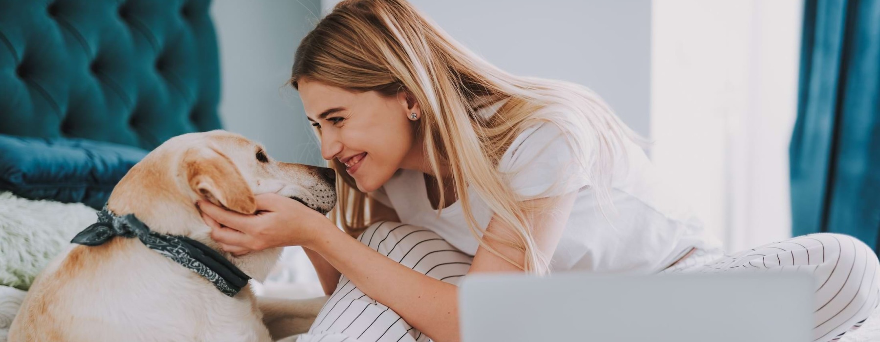 a woman with a laptop and a dog on a bed